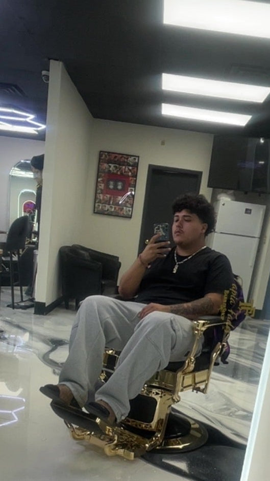 Person sitting in a barber chair in a salon, reflected in a mirror.